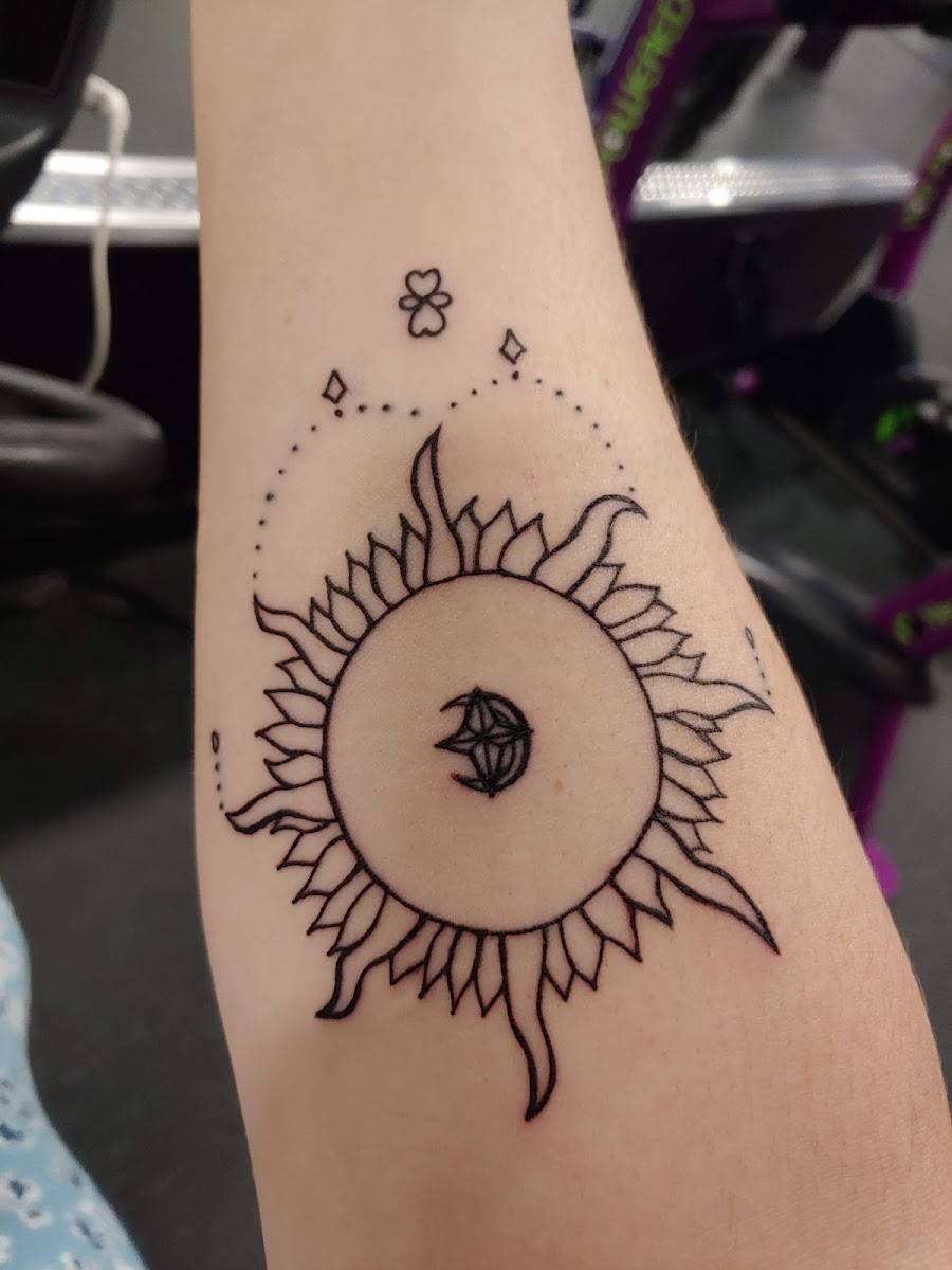 Fine line sun tattoo with dotwork on a forearm